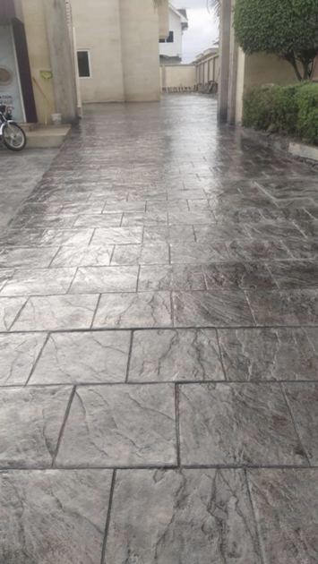 Photo d'un passage extérieur en béton imprimé gris, motif dalle