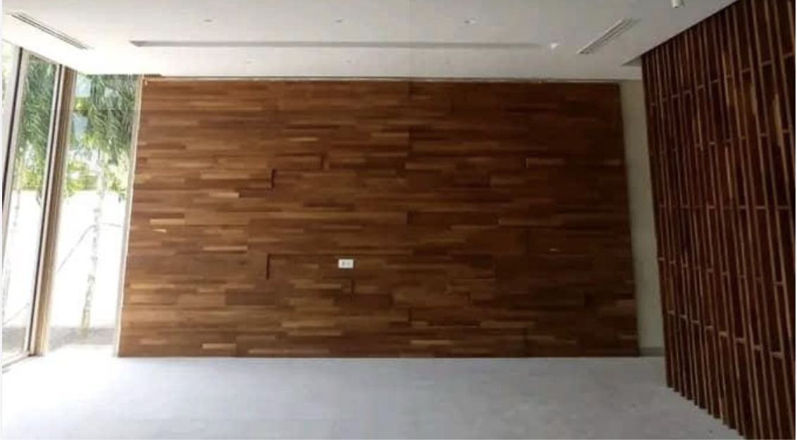 Photo d'un mur habillé de lames de bois massif posées en quinconce, à côté d'un claustra en bois